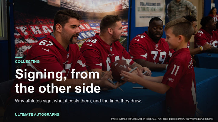 Arizona Cardinals players signing a football for a young fan at an autograph table